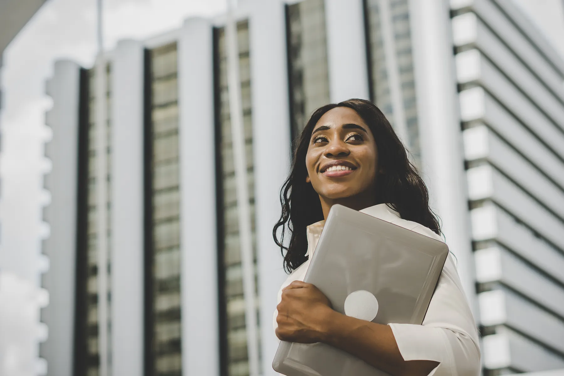 A businesswoman holding a laptop in a modern city